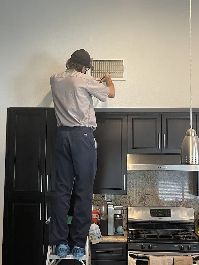 Technician inspecting an air vent during HVAC service in St. John